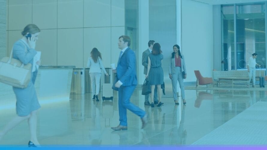 Business professionals walking in a modern office lobby with natural lighting and contemporary furnishings.