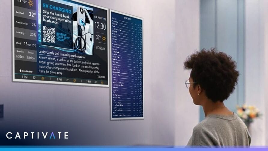Person looking at a digital display showing weather, EV charging station info, and news headlines in an indoor setting.