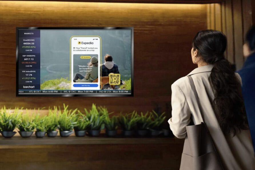 Person looking at a digital sign displaying streaming service content, with a row of plants below the screen.