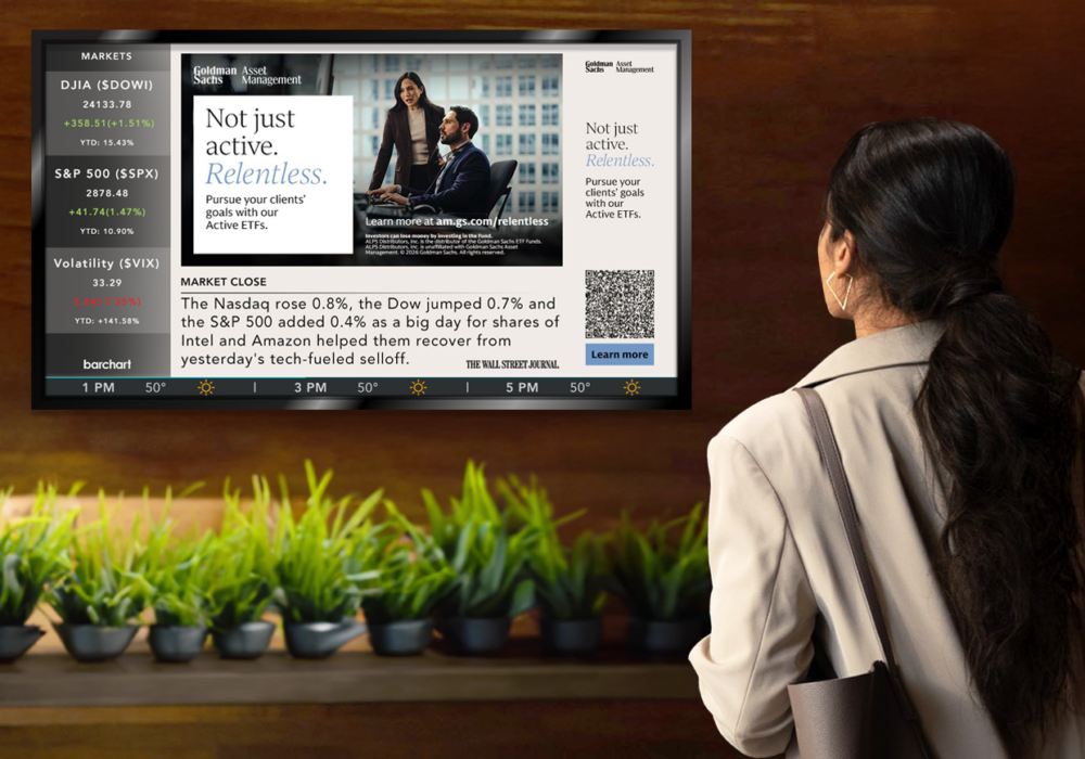 Person in business attire reading a news display on a wall-mounted screen, with plants below the screen.