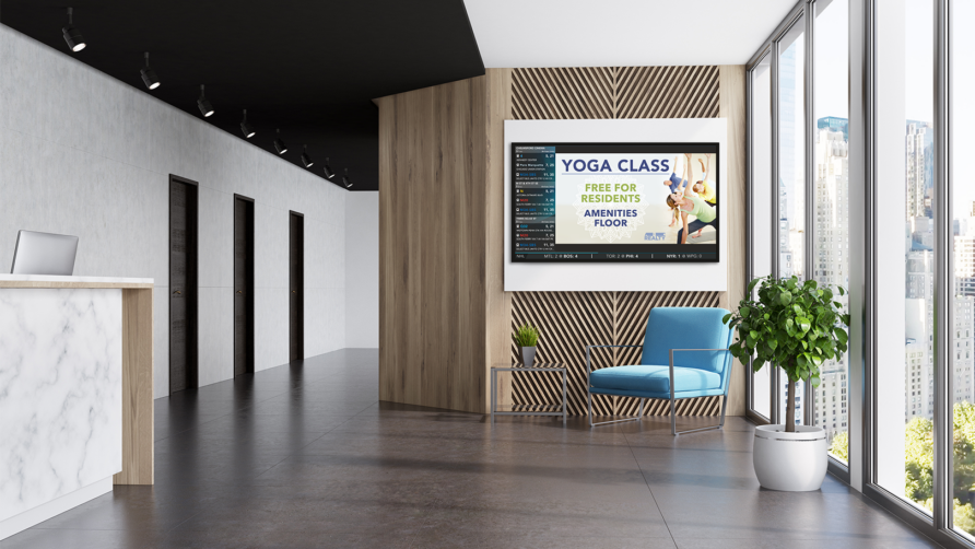 Modern lobby with digital screen advertising yoga class, blue chair, potted plant, large windows, and elevator doors.