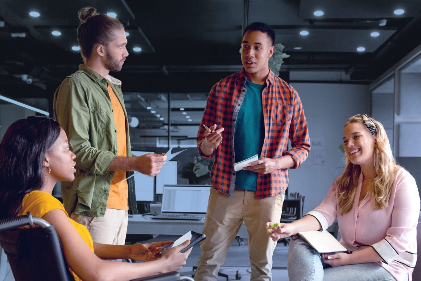 People in a modern office having a discussion, including a person in a wheelchair, promoting inclusivity and teamwork.