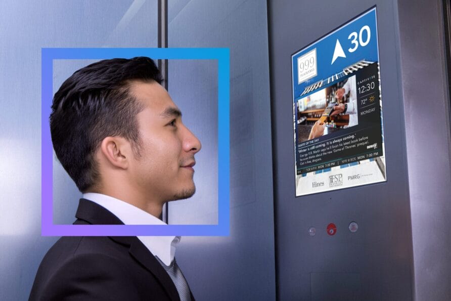 Man in suit looking at digital display next to elevator buttons, featuring a blue holographic interface.