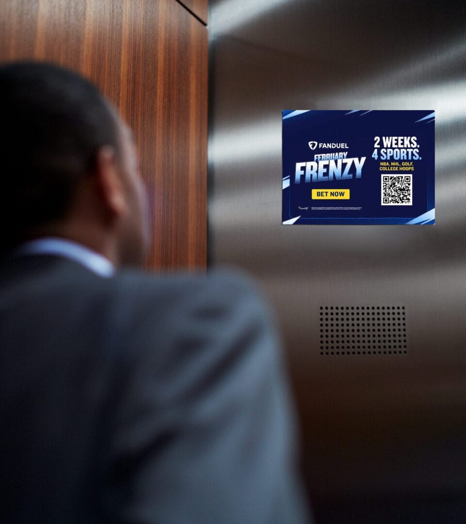 Man in suit looking at sports betting advertisement on digital screen inside an elevator.