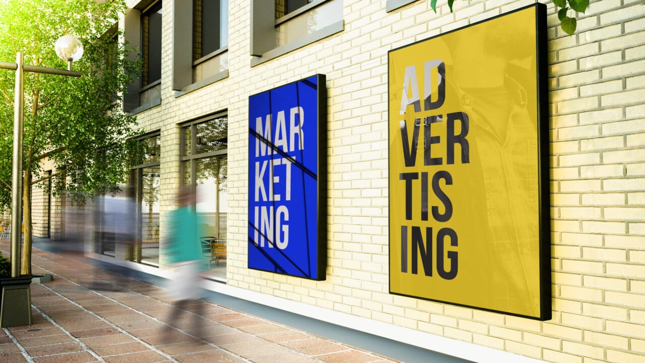Street view with motion-blurred people passing modern marketing and advertising posters on a brick wall.