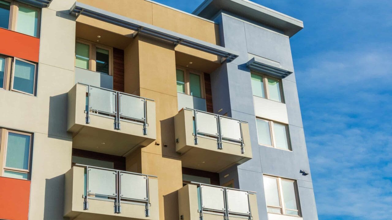 Modern apartment building with colorful facade and balconies against a clear blue sky.