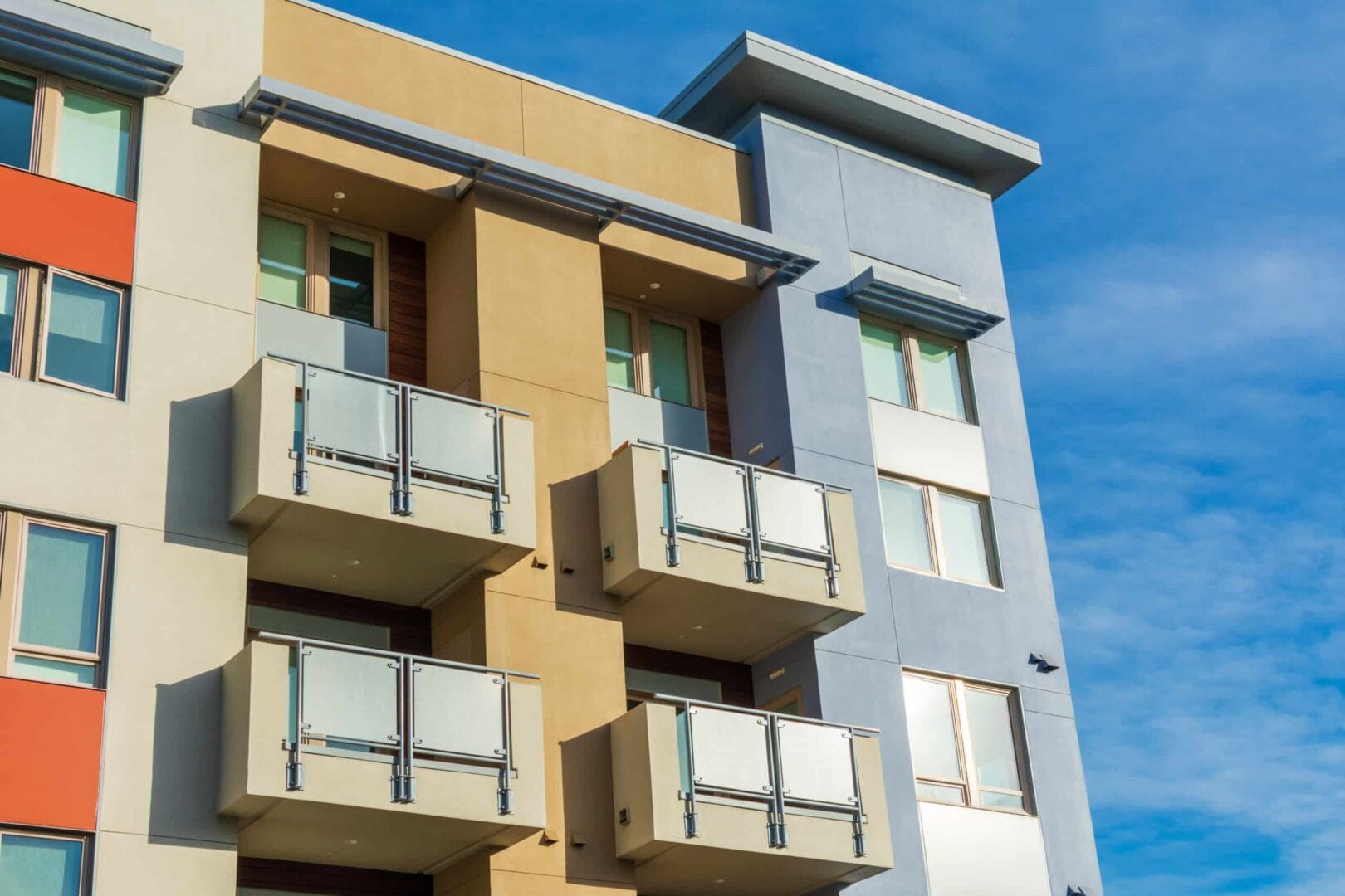 Modern apartment building with colorful facade and balconies against a clear blue sky.