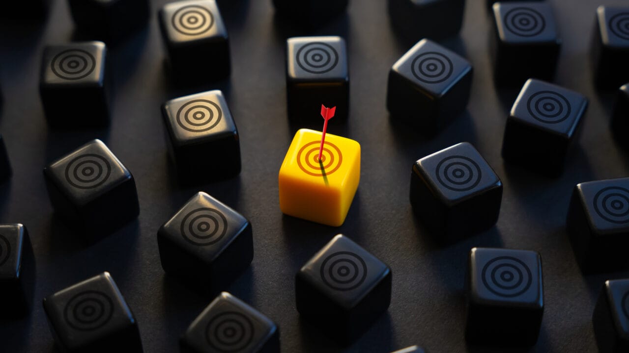 Yellow cube with a red arrow among black cubes, highlighting the concept of standing out or achieving a target.