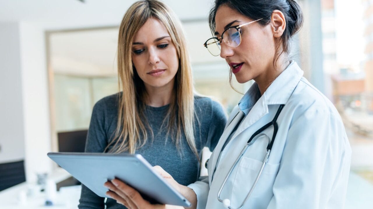 Doctor showing a digital tablet to a patient in an office setting.