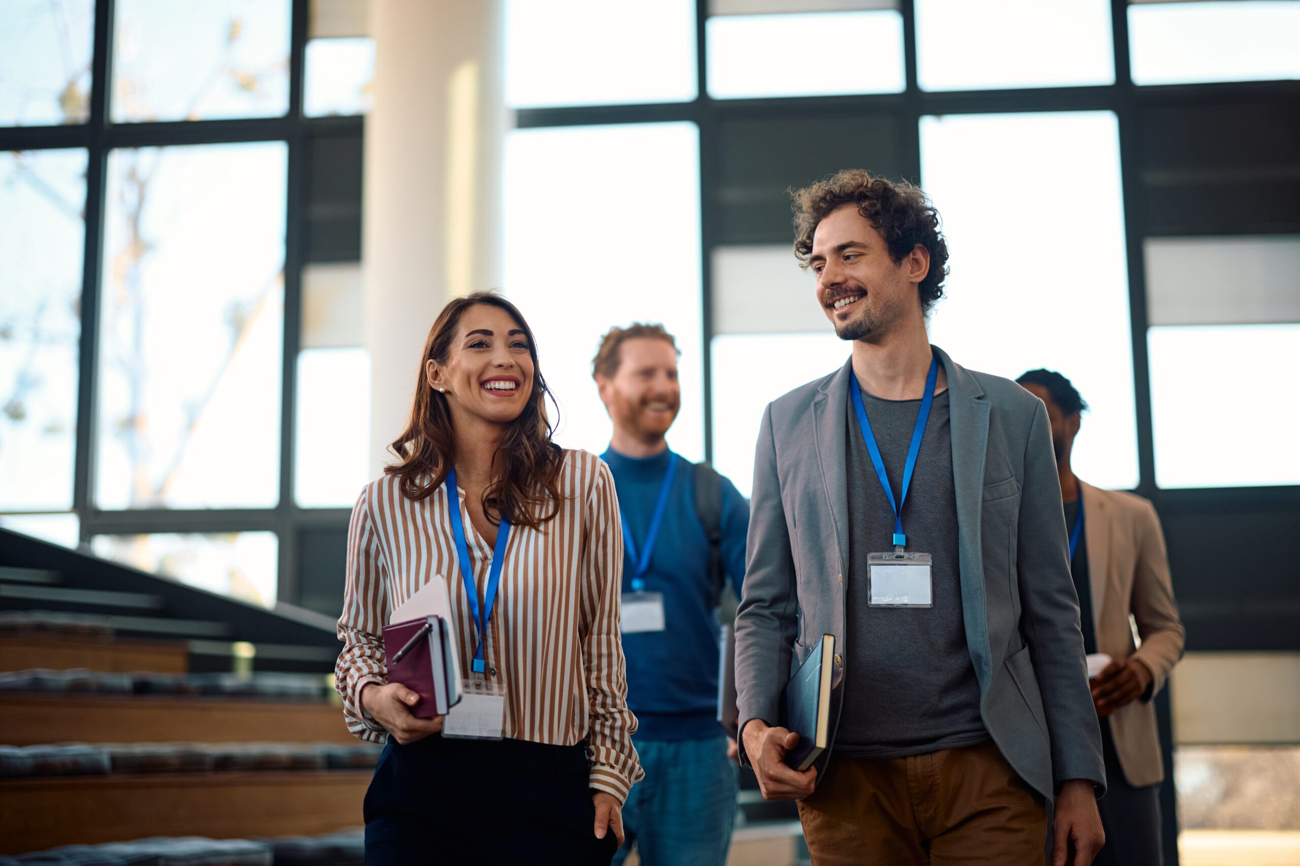Group of professionals with name tags walking and smiling in a modern office space
