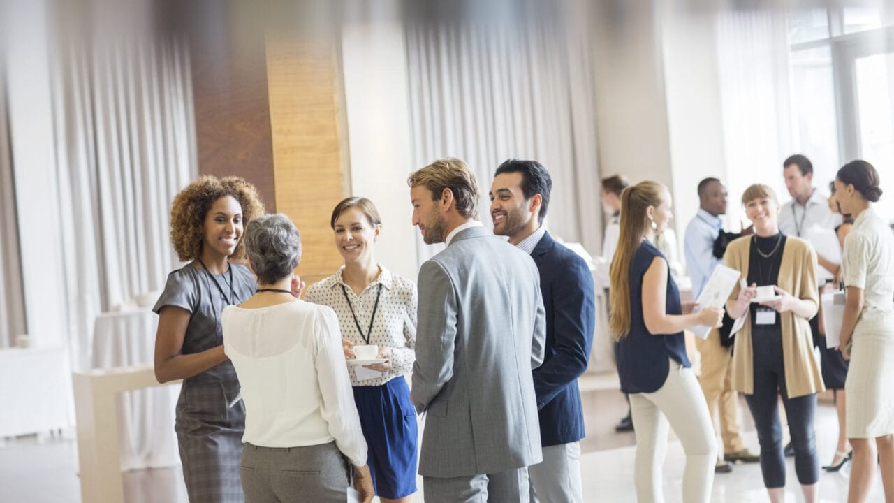 Professionals networking at a business event in a bright, modern venue.