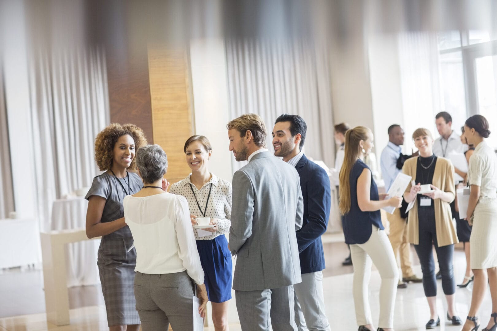 Professionals networking at a business event in a bright, modern venue.