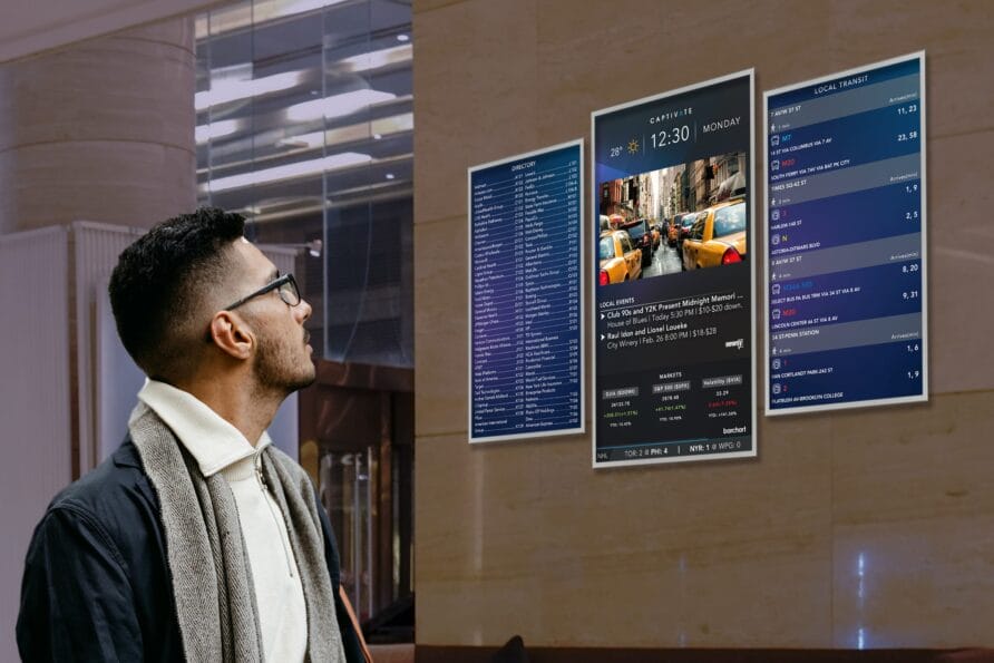 Man looking at digital menus displayed on a building exterior.