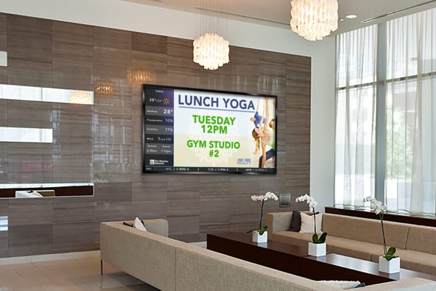 Lounge area with seating and large screen displaying lunch yoga session details.