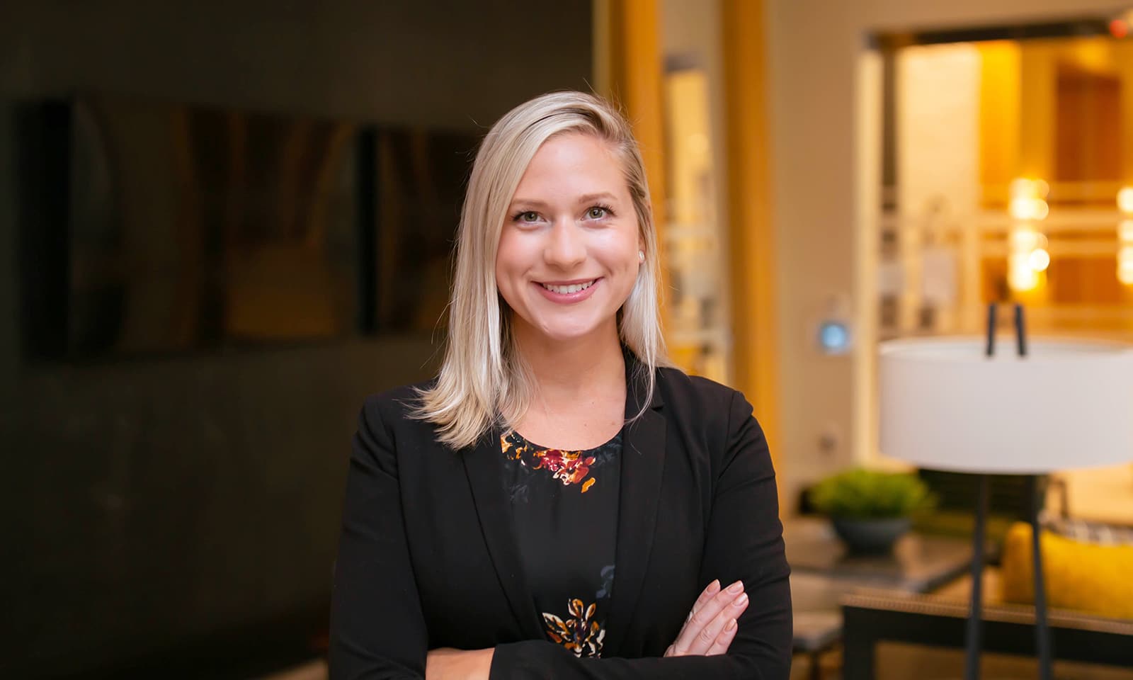 Person smiling in a professional setting with blurred background and modern decor.
