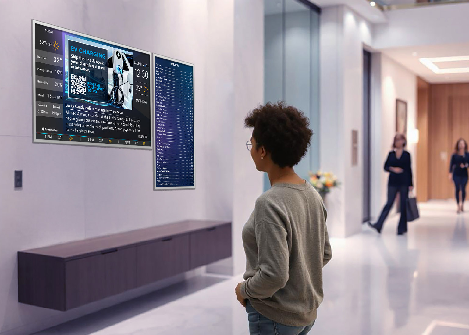 Person in a modern lobby observing digital displays with information and schedules on the wall.