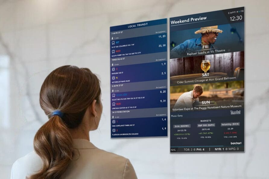 Person reading digital screens displaying flight information and travel advertisements in an airport terminal.