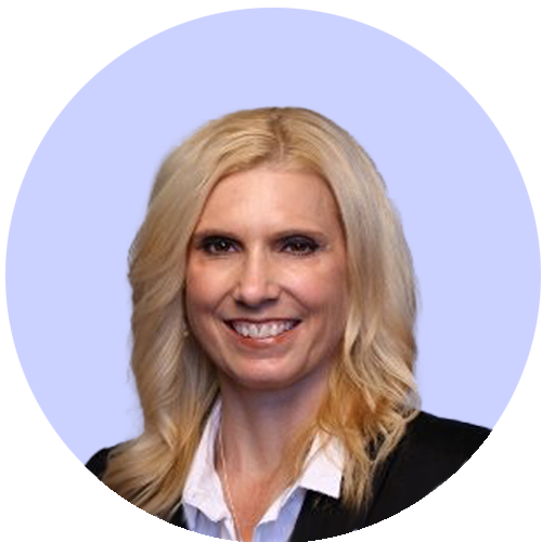 Smiling woman with long blonde hair in a black jacket and white shirt against a light purple background.