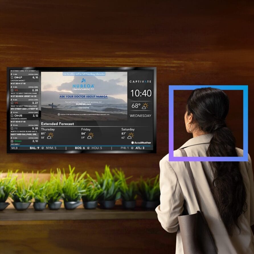 Person observing a wall-mounted digital screen displaying flight information in a lounge area with potted plants below.