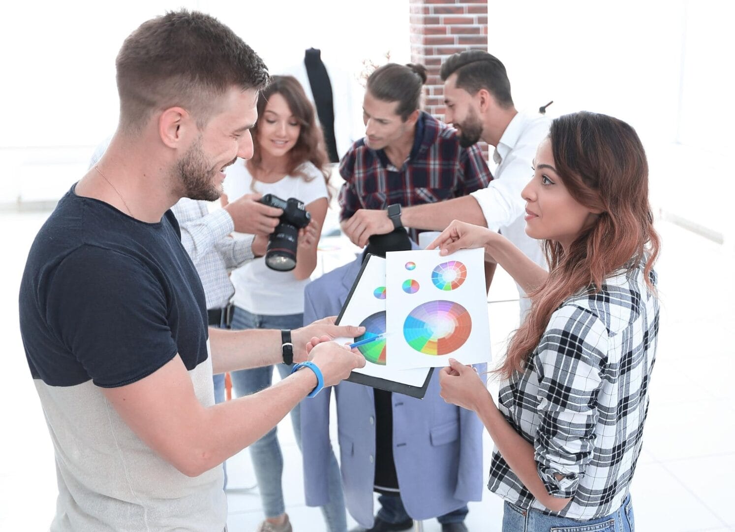 Group of young professionals discussing color schemes and photography in a bright office space.