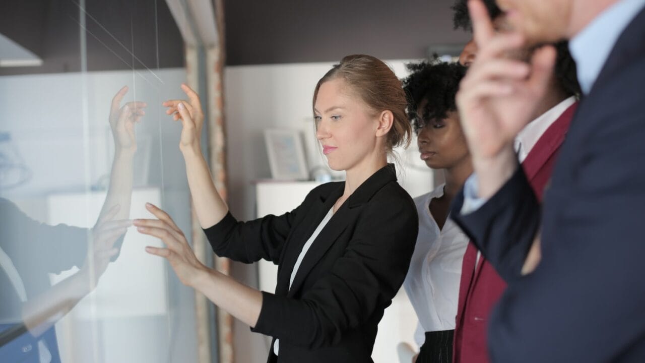 Business team examining a glass board with focused expressions.