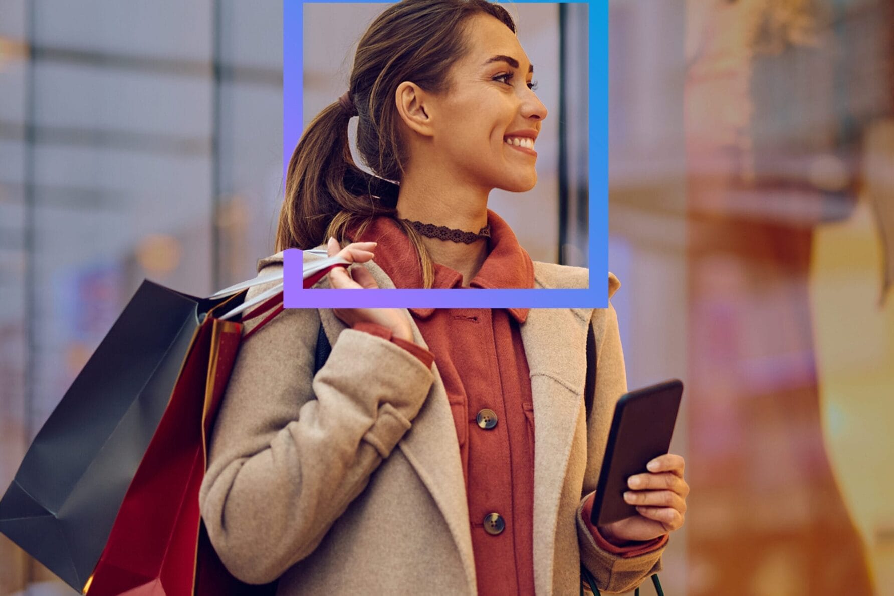 Woman shopping with bags and smartphone, smiling outdoors near glass storefront.